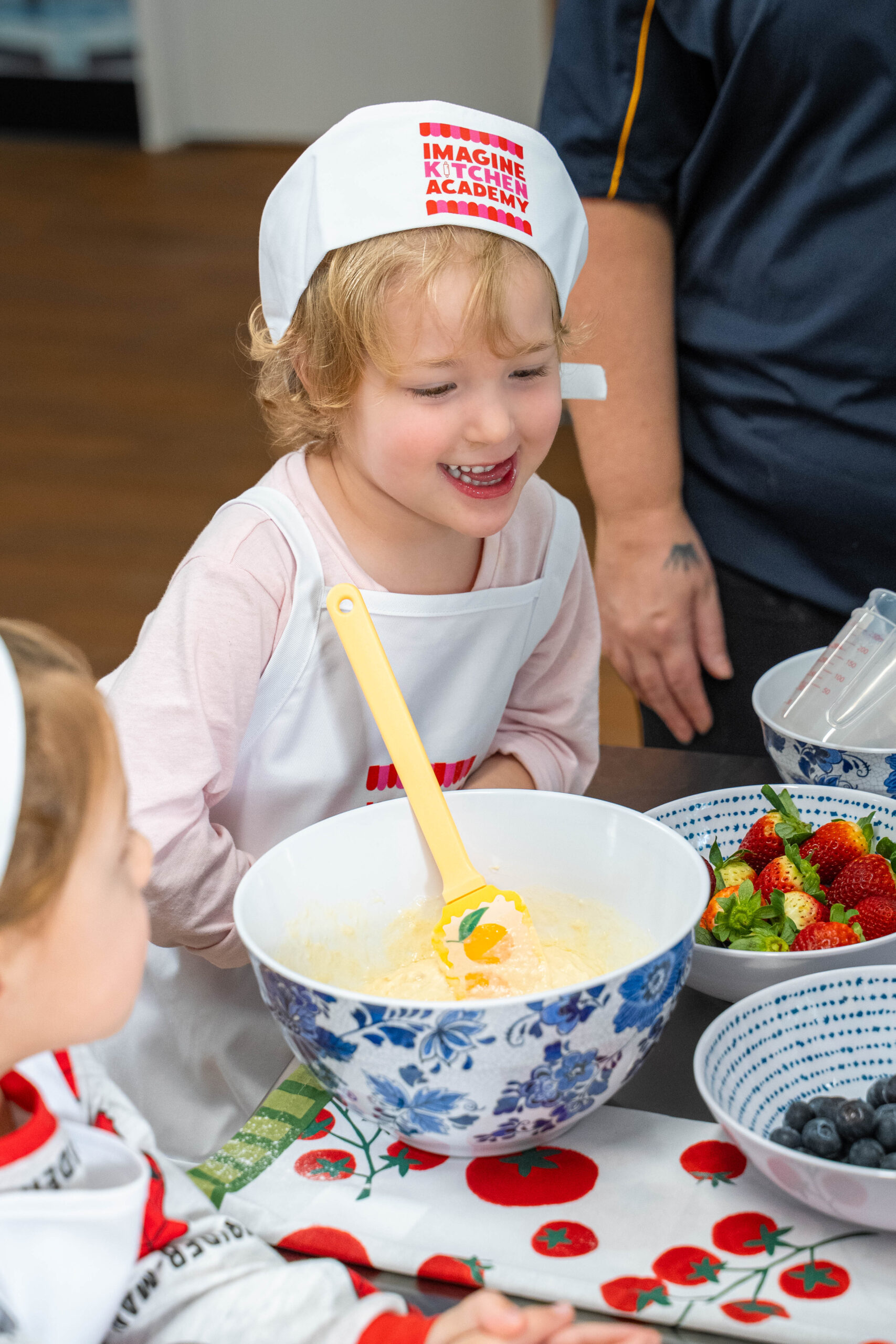 A child mixes ingredients with an educator during an Imagine Kitchen Academy cooking experience